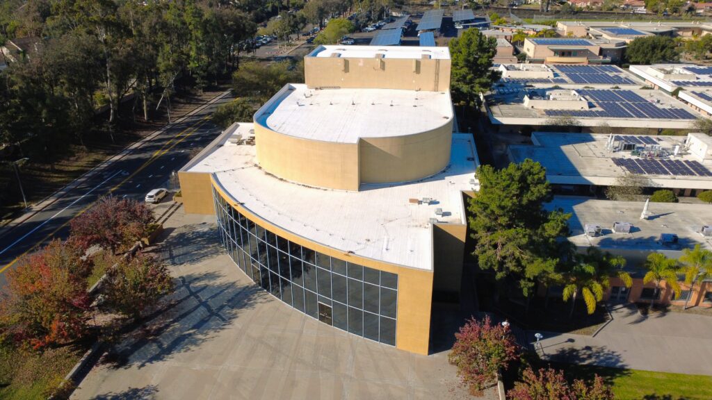 Aerial view of curved building with white roof