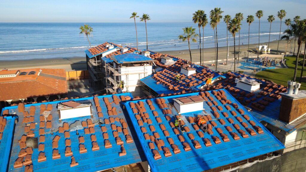 Workers installing terracotta roof tiles by beach