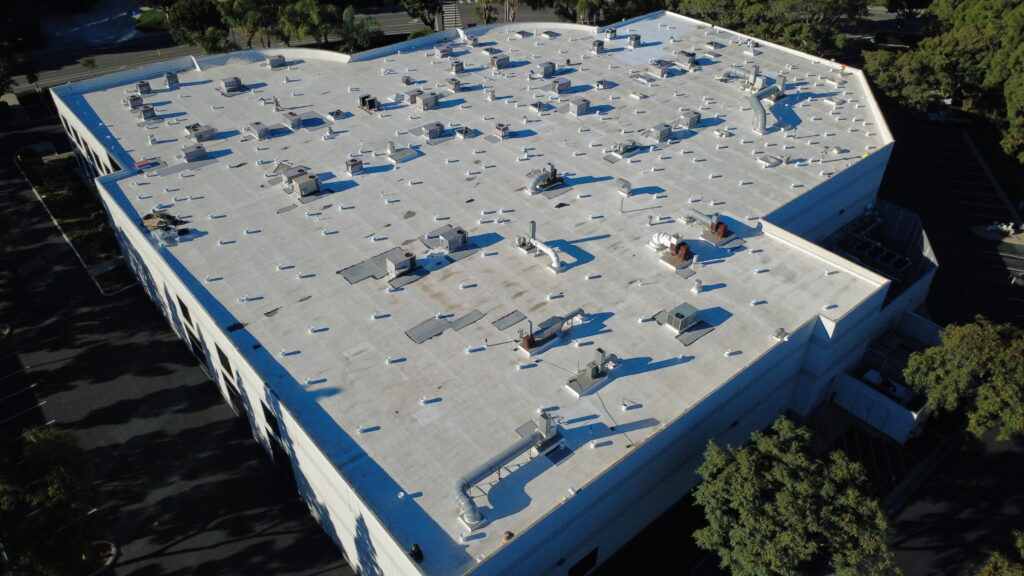 Aerial view of white commercial rooftop with vents