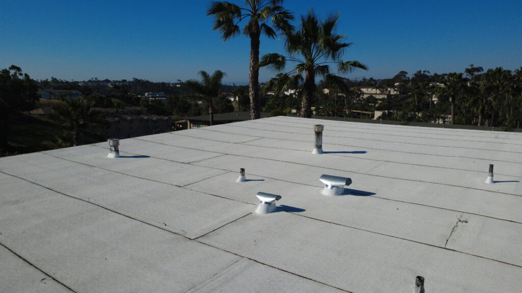 White flat roof with vents and palm trees