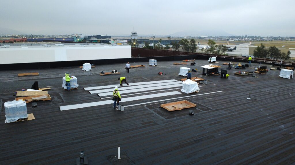 Roofing crew working near pallets and vents